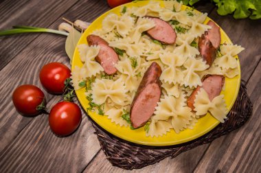 Makarna, ekmek, otlar ve kiraz domates dilimleri ile ızgara sosis. Bir ahşap rustik kahverengi zemin üzerinde. Üstten Görünüm. Yakın çekim