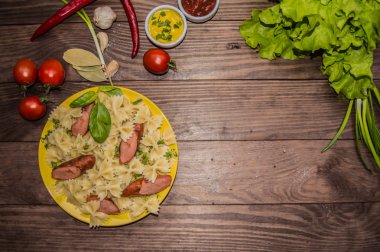 Makarna, ekmek, otlar ve kiraz domates dilimleri ile ızgara sosis. Bir ahşap rustik kahverengi zemin üzerinde. Üstten Görünüm. Yakın çekim