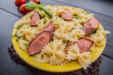 Makarna, ekmek, otlar ve kiraz domates dilimleri ile ızgara sosis dilim dilimlenmiş. Üstten Görünüm. ahşap siyah arka plan... . Yakın çekim