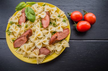 Makarna, ekmek, otlar ve kiraz domates dilimleri ile ızgara sosis dilim dilimlenmiş. Üstten Görünüm. ahşap siyah arka plan... . Yakın çekim