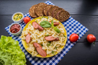 Makarna ve domates ile ızgara sosis dilim dilimlenmiş. Üstten Görünüm. ahşap siyah arka plan. Yakın çekim