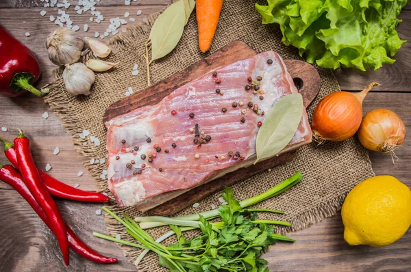 Pancetta cruda con erbe su un tavolo di legno. Vista dall'alto. Primo piano — Foto Stock