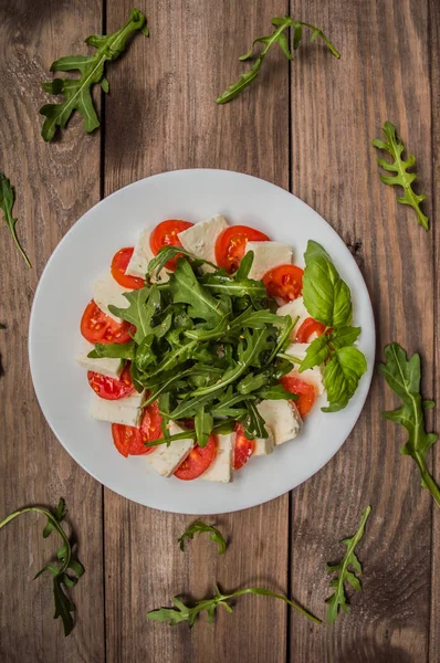 Salát z rukoly - Caprese. Dřevěné pozadí. Pohled shora. Detail — Stock fotografie