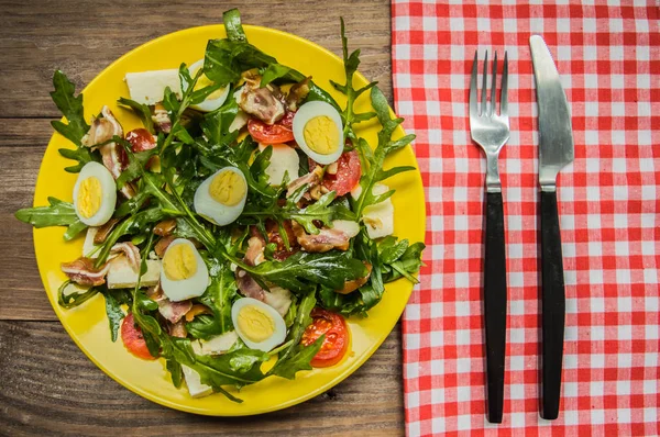 Insalata calda con pancetta e rucola. Sfondo rustico in legno. vista dall'alto — Foto Stock