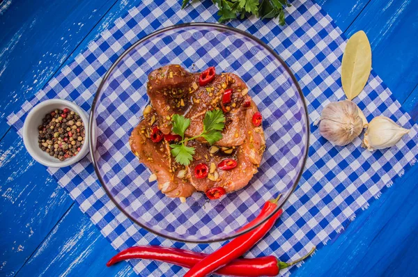 Marineret kød med krydderier og rød peber. Træblå baggrund. Øverste udsigt. Nærbillede - Stock-foto