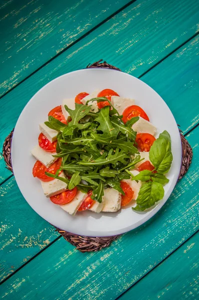 Caprese saláta - sült saláta kitûnõ. Fából készült türkiz háttér. Felülnézet. Közeli kép: — Stock Fotó