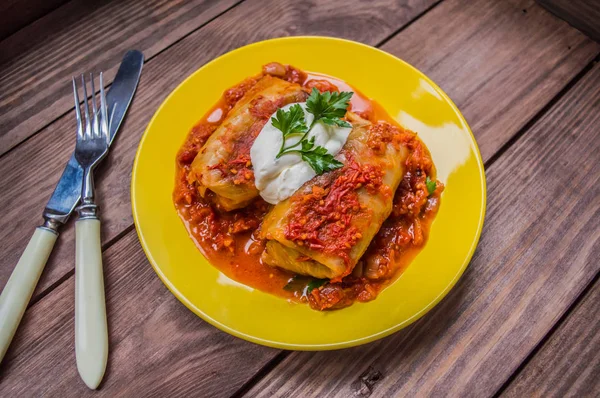 Akşam yemeği domates soslu lahana rulo ile dekore edilmiş maydanoz. Ahşap rustik arka plan. Üstten Görünüm. Yakın çekim