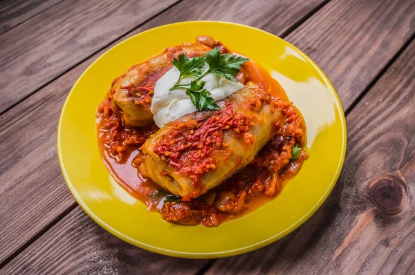 Akşam yemeği domates soslu lahana rulo ile dekore edilmiş maydanoz. Ahşap rustik arka plan. Üstten Görünüm. Yakın çekim