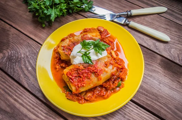 Akşam yemeği domates soslu lahana rulo ile dekore edilmiş maydanoz. Ahşap rustik arka plan. Üstten Görünüm. Yakın çekim