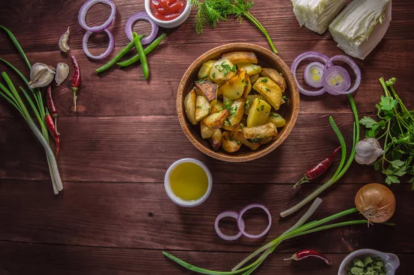 Pommes de terre rôties avec des légumes et des herbes sur un fond en bois, vue sur le dessus. Gros plan — Photo