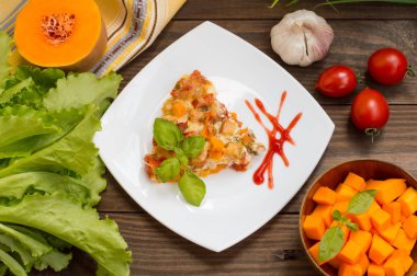 Tavuk ve beyaz bir kare plaka üzerinde kabak ile güveç. Ahşap rustik arka plan. Üstten Görünüm. Yakın çekim