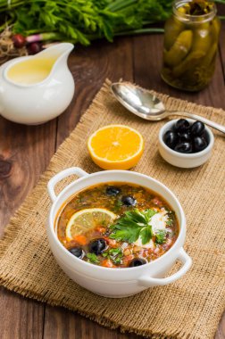 Solyanka, Rus yemekleri, çorba sıcak baharatlar ile dik et suyu üzerinde. Ahşap arka plan. Üstten Görünüm