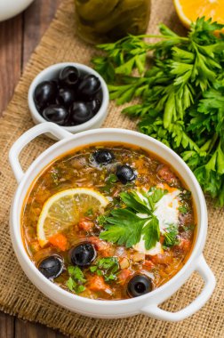 Solyanka, Rus yemekleri, çorba sıcak baharatlar ile dik et suyu üzerinde. Ahşap arka plan. Üstten Görünüm