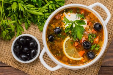 Solyanka, Rus yemekleri, çorba sıcak baharatlar ile dik et suyu üzerinde. Ahşap arka plan. Üstten Görünüm