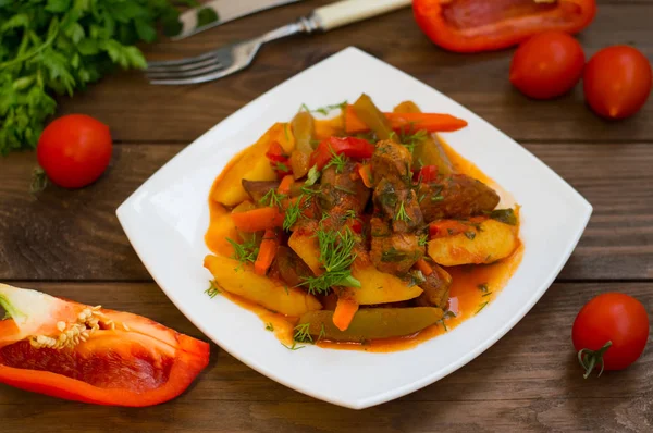 Stufato con patate, carote, sottaceti, pomodori e peperoncini. Azu di tartaro su un piatto quadrato bianco. Sfondo rustico in legno. Vista dall'alto. Primo piano — Foto Stock