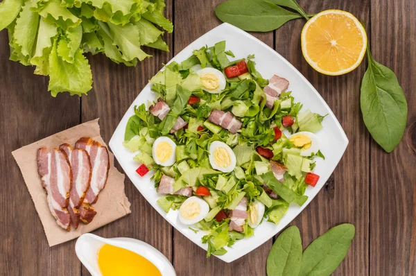 Salade aux épinards, œufs de caille et bacon. Table en bois. Vue de dessus. Gros plan — Photo