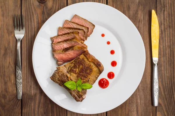 Vzácné středně hovězí steak na grilu s barbecue omáčkou. Dřevěný stůl. Pohled shora. Detail — Stock fotografie