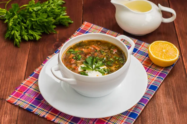 Solyanka, Russian dishes, soup on a steep meat broth with hot spices. Wooden background