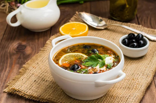 Solyanka, Rus yemekleri, çorba sıcak baharatlar ile dik et suyu üzerinde. Ahşap arka plan. Üstten Görünüm