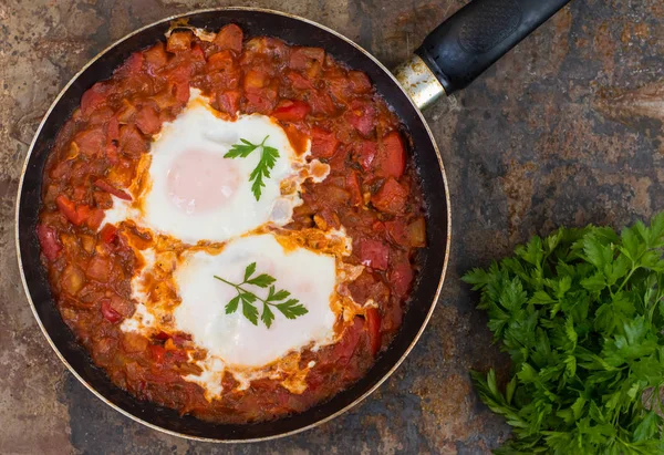 Shakshuka i en stekpanna. Traditionella judiska maträtt. Träbord. Ovanifrån. Närbild — Stockfoto