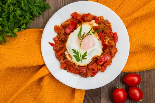 白いプレートに Shakshuka。ユダヤ人の伝統的な料理。木製のテーブル。平面図です。クローズ アップ — ストック写真