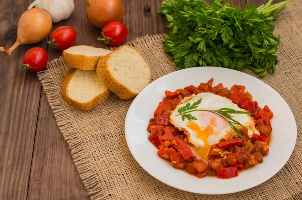 Shakshuka σε ένα λευκό πιάτο. Παραδοσιακό εβραϊκό πιάτο. Ξύλινο τραπέζι. Το Top view. Γκρο πλαν — Φωτογραφία Αρχείου