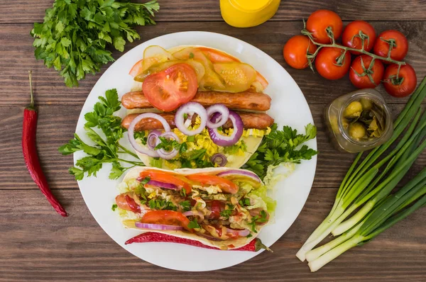 Ingredienti per un picnic composto da verdure e salsicce grigliate su fondo rustico in legno, vista dall'alto. Primo piano — Foto Stock