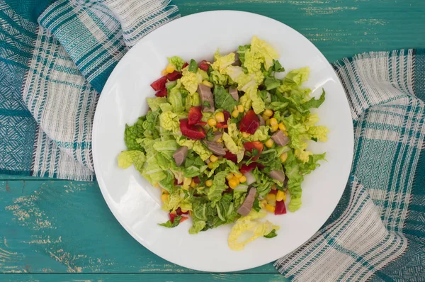Salade van rundvlees tong, Chinese kool, paprika, maïs, peterselie en basilicum. Houten achtergrond. Bovenaanzicht — Stockfoto