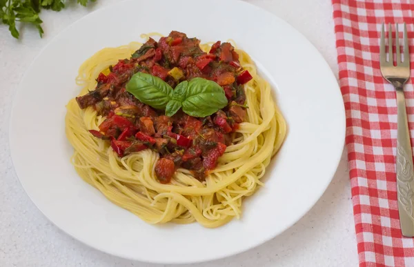 Итальянская паста с помидорами, капсикумом и говядиной на белом столе — стоковое фото