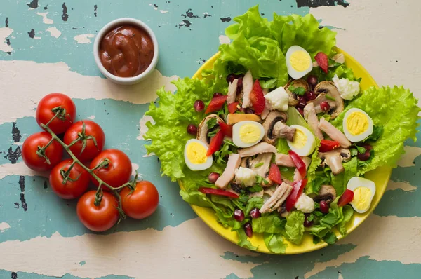 Salată cu ciuperci, pui, ouă de prepeliță, ardei, salată verde și rodie, pe o masă veche. Privire de sus — Fotografie, imagine de stoc