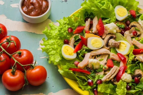 Mantar, tavuk, bıldırcın yumurtası, kırmızı biber, marul ve eski bir tabloda nar salatası. Üstten Görünüm — Stok fotoğraf