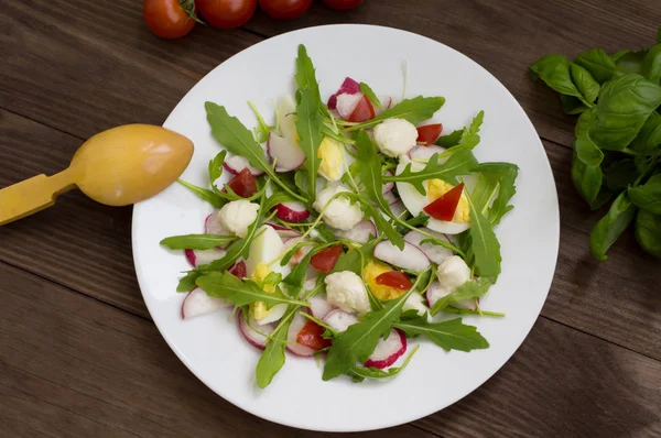 Salada com rabanetes, rúcula, ovo de galinha e codorniz em um fundo de madeira, vista superior — Fotografia de Stock