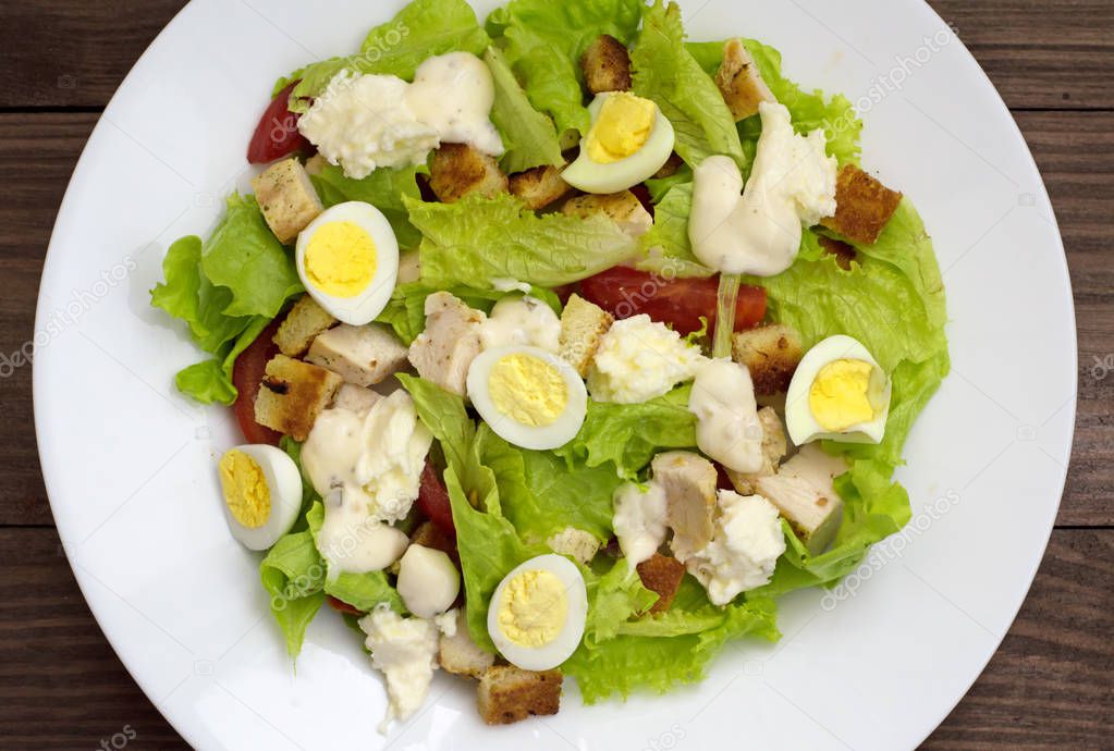 Salad with grilled chicken, lettuce and mozzarella cheese on a wooden background. Top view. Close-up
