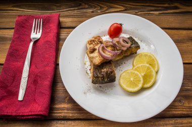 Kızarmış balık fileto limon ve beyaz tabakta domates. Ahşap arka plan. Üstten Görünüm. Yakın çekim