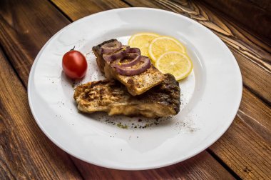 Kızarmış balık fileto limon ve beyaz tabakta domates. Ahşap arka plan. Üstten Görünüm. Yakın çekim