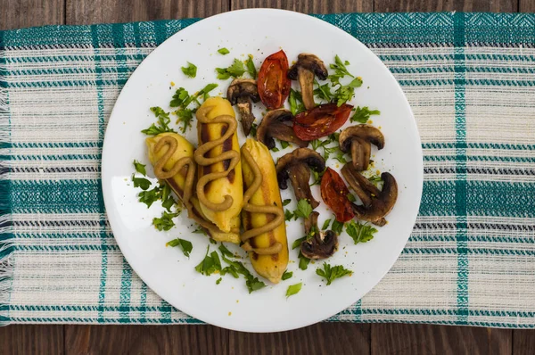 Pomme de terre Zrazy farcie avec des champignons de viande et des tomates grillées sur une assiette blanche. Fond en bois. Vue de dessus. Gros plan — Photo