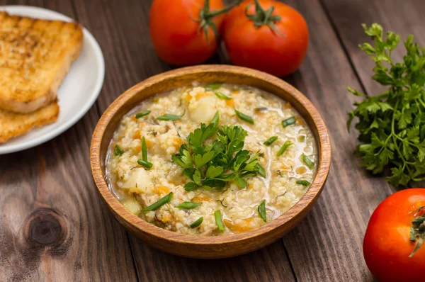 Porridge di grano con carne preparata su un fuoco in tavolo rustico di piatto di legno. Vista dall'alto — Foto Stock