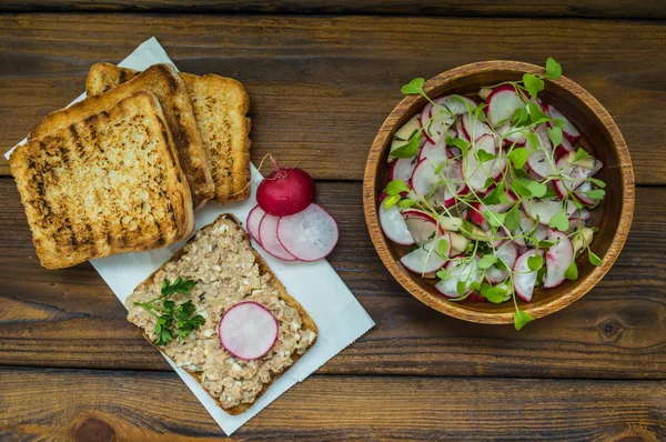 Salat mit Radieschen, Äpfeln, Gemüse und einer Sandwich-Fischpastete. Holzuntergrund. Ansicht von oben. Nahaufnahme — Stockfoto