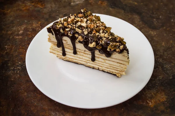 Napoleon cake covered with chocolate and walnuts  raisins on an old table. Top view. Close-up — Stock Photo, Image