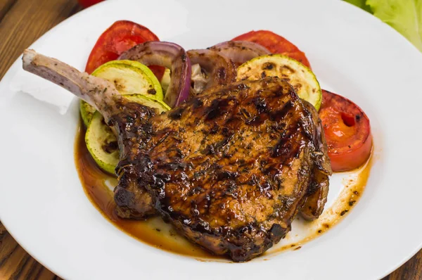 Bistecca di maiale sull'osso grigliata con verdure. Sfondo in legno. Vista dall'alto. Primo piano — Foto Stock