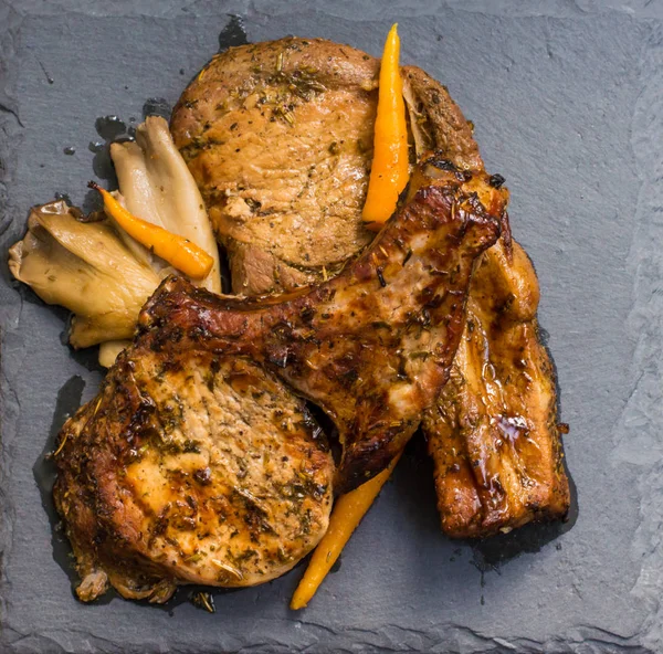 Vepřový steak na kosti na grilu a hlívy, sloužil kámen. Pohled shora. Detail — Stock fotografie