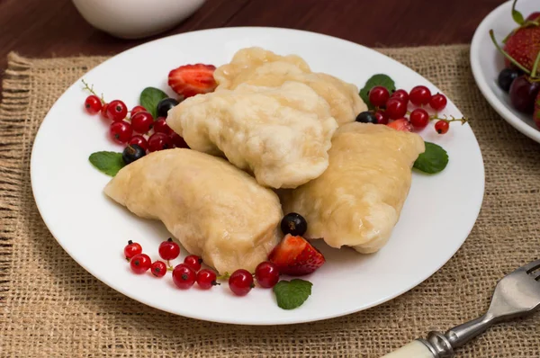 Gnocchi con fragole su uno sfondo di bacche selvatiche. Tavolo rustico in legno. Primo piano — Foto Stock