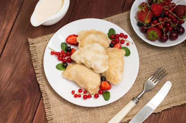 Gnocchi con fragole su uno sfondo di bacche selvatiche. Tavolo rustico in legno. Vista dall'alto. Primo piano — Foto Stock