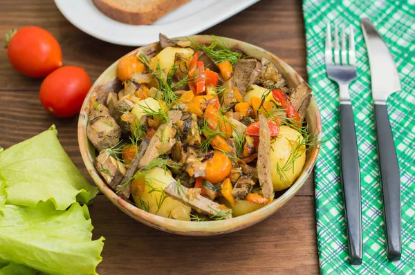 Fegato brasato con cipolle, carote, patate e spezie sul piatto di pietra. Sfondo in legno. Primo piano — Foto Stock