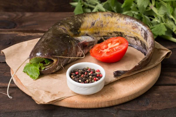 Poisson-chat frais sur une planche à découper. Fond en bois. Gros plan — Photo