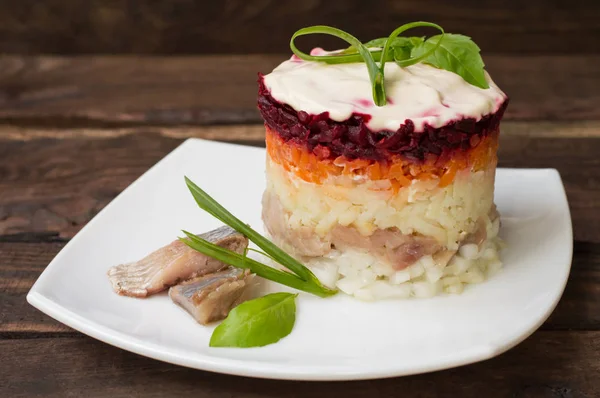 Shuba salade. Gekookte bieten, wortelen, aardappelen, uien, haring en mayonaise. De klassieke Russische keuken. Restaurant de levering. Houten tafel. Close-up. Bovenaanzicht — Stockfoto