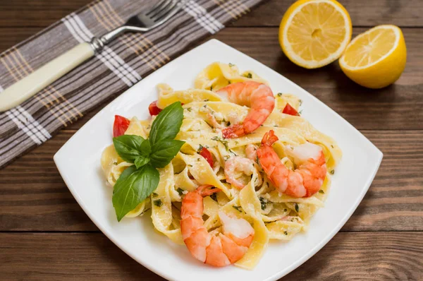 Fettuccine makarna Krema soslu king ile bir plaka üzerinde ahşap masa prawns. Üstten yatay görünüm. Sayfanın Üstü. Yakın çekim — Stok fotoğraf