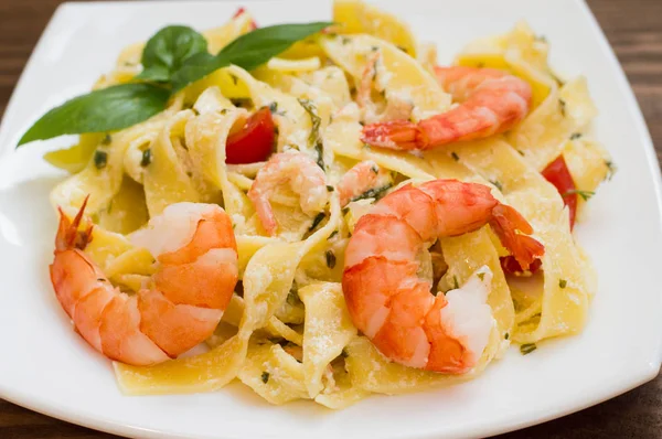 Fettuccine pasta in cream sauce with king prawns on a plate  the wooden table. Horizontal view from above. Top . Close-up