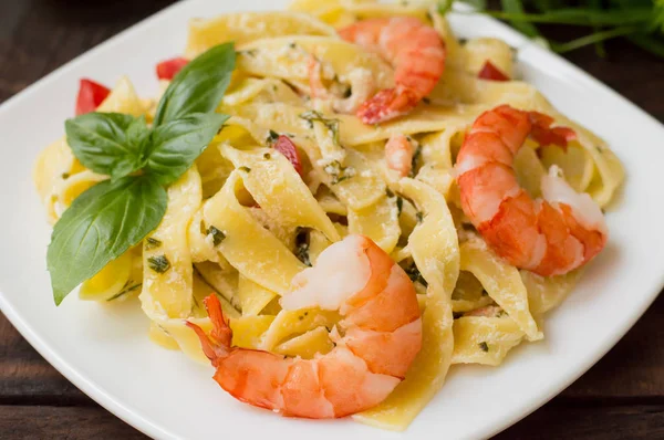 Fettuccine pasta in roomsaus met koning garnalen op een plaat de houten tafel. Horizontale weergave van bovenaf. Boven. Close-up — Stockfoto