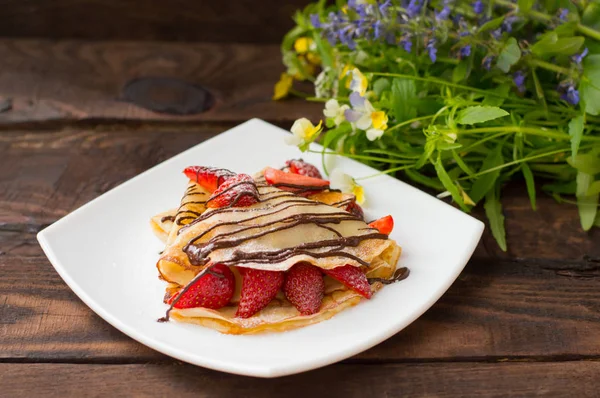Pancakes with strawberries, topped  chocolate. Wooden table. Top view — Stock Photo, Image